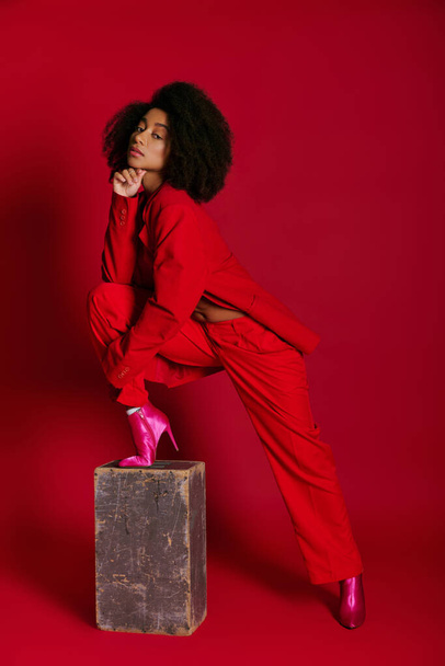 modelo feminino afro-americano muito na moda em traje sexy olhando para a câmera no fundo vermelho - Foto, Imagem