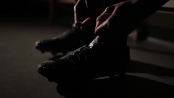 Jalkapalloilija sitomassa kengännauhojaan valmistautuakseen otteluun. Elokuvallinen laukaus linssin soihdulla
 - Materiaali, video