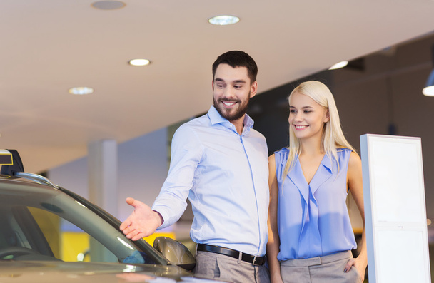 happy couple buying car in auto show or salon - Fotoğraf, Görsel