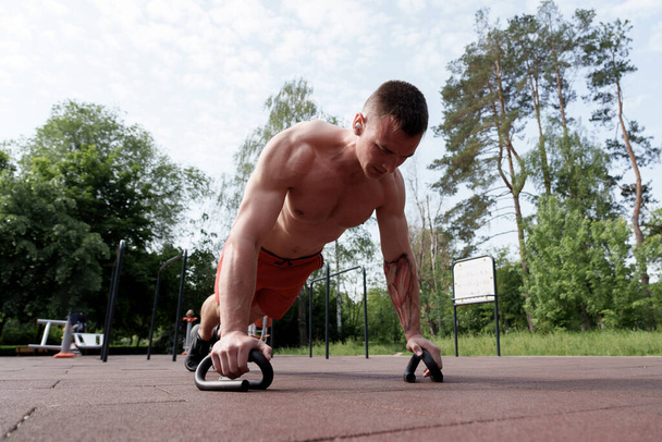 Решительный спортсмен мужского пола участвует в сложных тренировках на открытом воздухе, демонстрируя силу и фокус - Фото, изображение