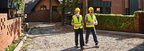 安全ベストのハンサムな建設労働者 歩いて話し合い場所,コテージビルダー,バナー - 写真・画像