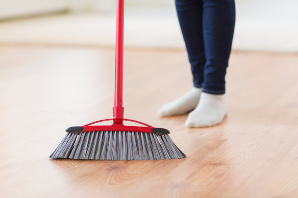 close up of woman legs with broom sweeping floor - Foto, Imagem