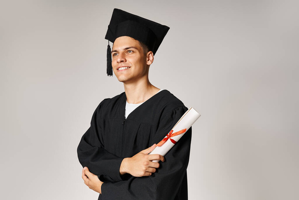 attraktive junge Studentin im Diplom-Outfit lächelt und freut sich mit dem Diplom in der Hand - Foto, Bild