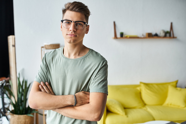charismatic man in his 20s with brown hair and vision glasses in living room folding cross arms - Photo, Image