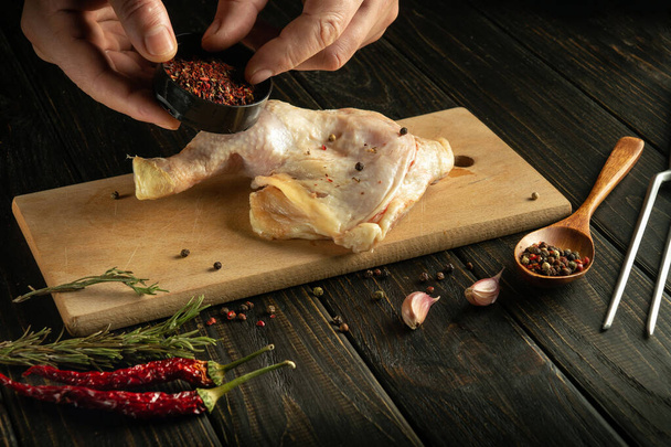 Кухар приправляє курячу ногу спеціями. Концепція приготування курячого м'яса зі спеціями та перцем. - Фото, зображення