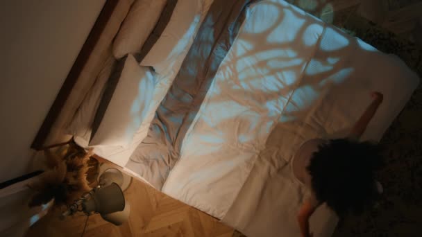 Top näkymä ylhäältä kaunis nuori nainen illalla kuuluvat sängylle pehmeä patja väsynyt loppuun Afrikkalainen Amerikan tyttö levätä rentoutua työpäivän jälkeen yöunet lepää omassa makuuhuoneessa sisustus - Materiaali, video