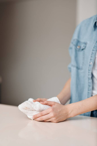 Limpio y cuidado: Una mujer limpiando las superficies del hogar con una botella de trapo y aerosol - Foto, Imagen