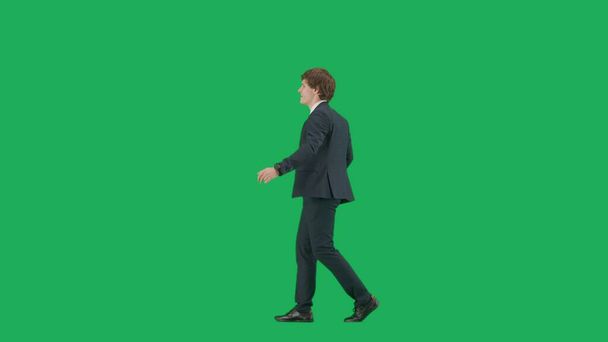 Modern businessman creative advertisement concept. Portrait of male model in suit on chroma key green screen background . Stylish young businessman in trendy suit is dancing. - 写真・画像