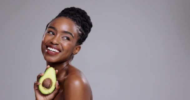Szépség, avokádó és a nő nevetnek a stúdióban az egészséges kozmetikumok, táplálkozás vagy méregtelenítő szürke alapon. Boldog afrikai modell gondolkodás a gyümölcsökről a fenntartható előnyök, az öko bőrápolás vagy a mockup diéta érdekében. - Felvétel, videó