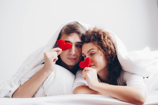 Love couple lying on white bed blanket hold heart symbol valentine concept - Photo, Image