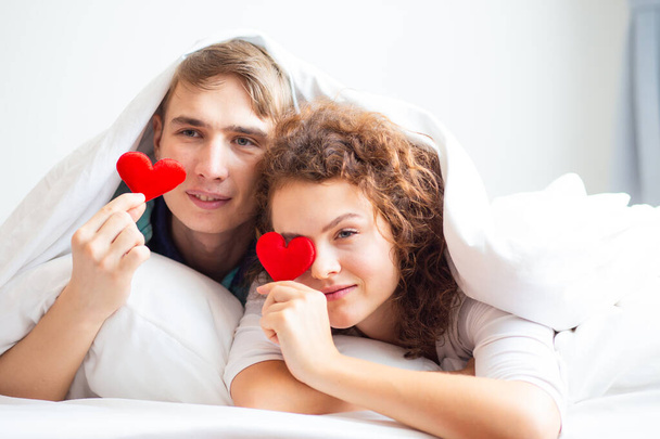 Amor pareja acostado en blanco cama manta celebrar corazón símbolo valentine concepto - Foto, Imagen