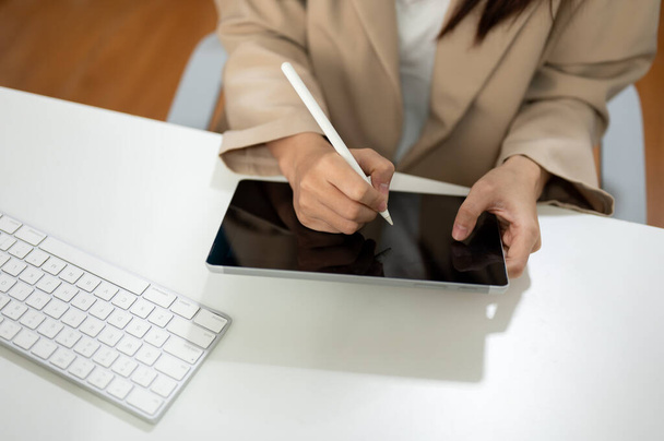 Immagine ravvicinata di una donna d'affari che usa il suo tablet digitale sulla scrivania del suo ufficio. Concetto di persone e tecnologia - Foto, immagini