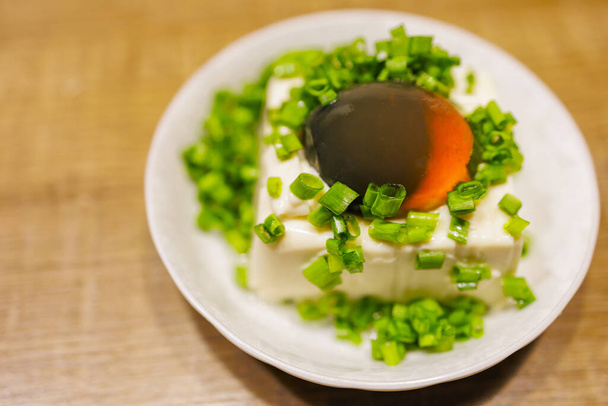 een bord van prachtige eeuw ei tofu, bestrooid met verse groene uien - Foto, afbeelding