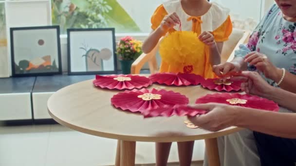 Imagen recortada de la familia asiática elaborando decoraciones de papel rojo y amarillo para las vacaciones Tet en casa - Metraje, vídeo