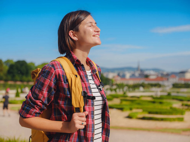 Женщина-туристка путешествует по Австрии, столице Вены. летняя женская самостоятельная поездка в Европу, счастливая молодая женщина, гуляющая в парке возле дворцового комплекса Бельведер в стиле барокко. - Фото, изображение