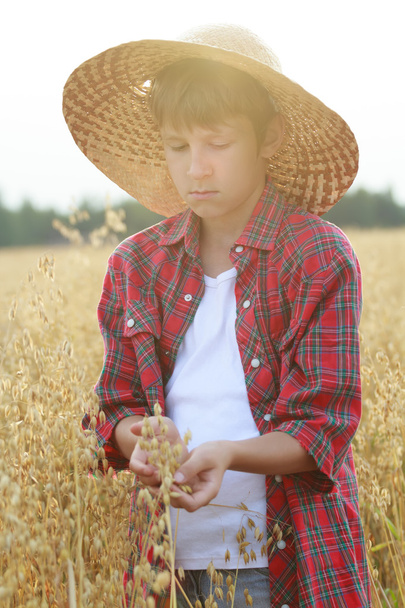 Retrato de un adolescente granjero sosteniendo semillas de avena con conchas exteriores en palmeras ahuecadas con destello solar
 - Foto, Imagen