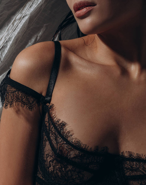 Close-up view to sexy woman posing in lacy black bra in dark studio. Seductive, sexy lingerie. - Photo, Image