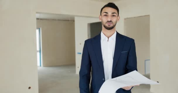Portrait of elegant real estate agent in the new building for sale holding plan in hands ready to sell house for potentail clients. - Footage, Video