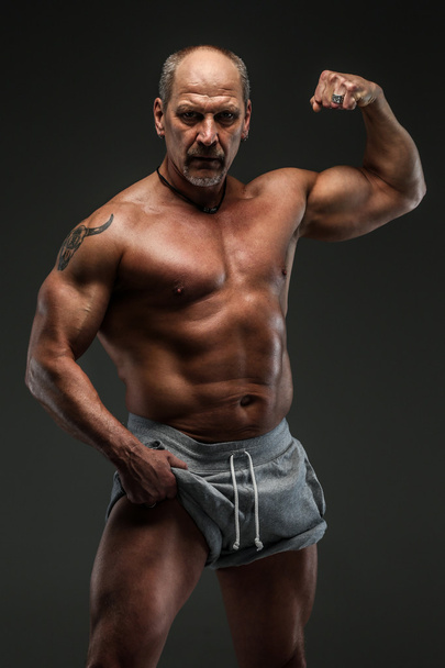Мускулистый мужчина средних лет показывает свои мускулы
 - Фото, изображение