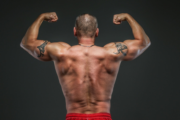Мускулистый мужчина средних лет показывает свои мускулы
 - Фото, изображение