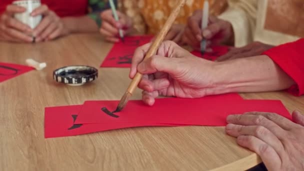 テトの間に赤い紙に書道を書いている間,黒インクを使用しているベトナム人の手を閉じます - 映像、動画
