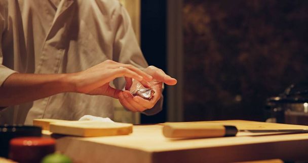 Kädet, resepti ja kokki ruoanlaitto sushia ravintolassa perinteisen japanilaisen keittiön tai lautasen lähikuva. Keittiö, ainekset äyriäisten valmistukseen ja henkilö, joka työskentelee gourmet-ruoan tai aterian kanssa pöydällä. - Valokuva, kuva