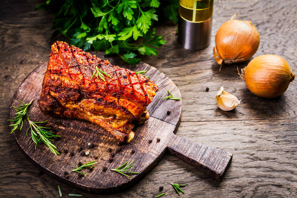 Grilled pork belly with crispy skin, with onion and herbs  on wooden background - Photo, Image