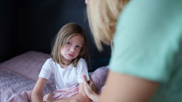 Een verdrietig meisje communiceert thuis met mama. Tactiel contact van kinderen en ouders concept - Foto, afbeelding