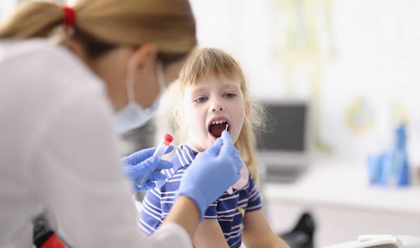 保護服の研究室のアシスタントの肖像は、子供の喉から綿棒を取ります,自宅での手順,コロナウイルスのための研究室テスト.検疫、 covidの概念 - 写真・画像
