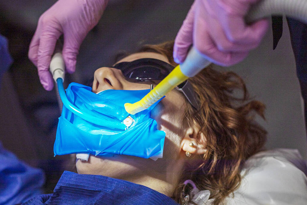 asystent usuwa nadmiar śliny z ciała pacjenta z przyrządem dentystycznym. - Zdjęcie, obraz