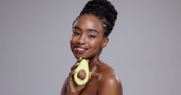 Avokádó, szépség és arc a nő a stúdióban az egészséges kozmetikumok, táplálkozás és étrend szürke alapon. Portré, boldog afrikai modell vagy gyümölcs a fenntartható bőrgyógyászathoz, öko-előnyökhöz és bőrápoláshoz. - Felvétel, videó