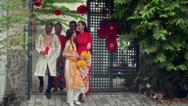 Široký záběr velké vietnamské rodiny v červené a žluté tradiční kostýmy slaví Tet venku - Záběry, video