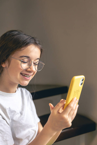 Uma adolescente de óculos e aparelho se comunica via videochamada com um smartphone. - Foto, Imagem