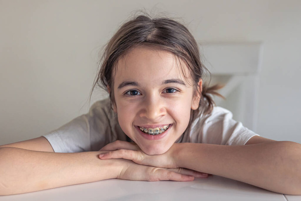 Una adolescente divertida mira a la cámara y muestra frenos en los dientes. Concepto de tratamiento ortodóncico y salud dental. - Foto, imagen