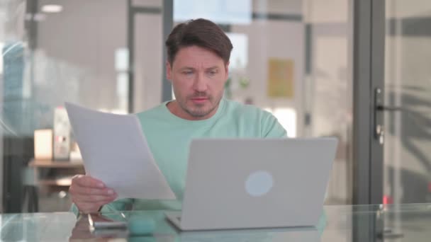 Людина шокована втратами під час роботи над документами та ноутбуками - Кадри, відео