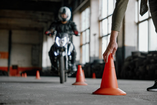 Motorbike driving school lesson with instructor putting cone on track front of student. Indoor moto drome training center - Photo, Image
