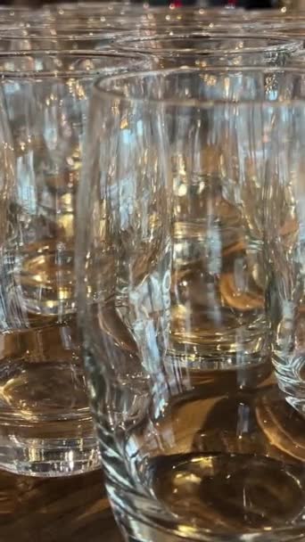 Auf der eleganten Theke reihen sich leere Gläser aneinander. Die glasklaren Gefäße warten auf die geschickten Hände der Barkeeper, die bereit sind, sie mit handgefertigten Trankopfern zu füllen. Hohe Qualität  - Filmmaterial, Video