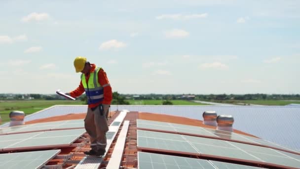Mérnökök villanyszerelők technikus dolgozik a tetőtéri ipari üzem telepítése napelemek alternatív energia segítségével elektromos fúrók szilárdan rögzítő kábelpályák villamos energia - Felvétel, videó