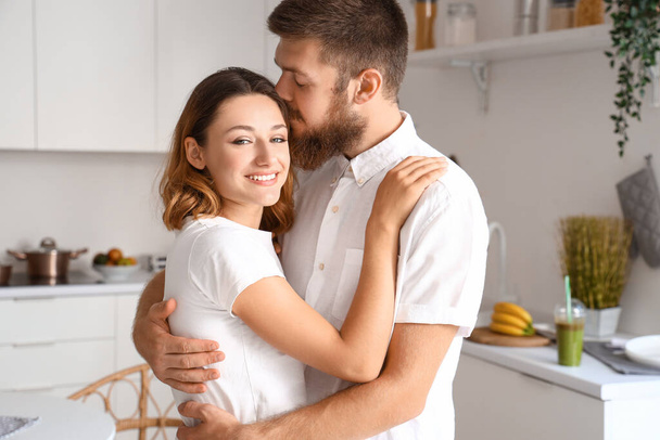 Ευτυχισμένο ζευγάρι ερωτευμένο αγκαλιάζει στην κουζίνα - Φωτογραφία, εικόνα