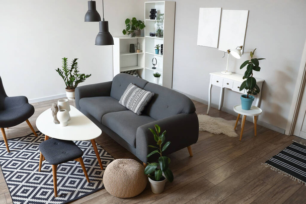 Interior de la elegante sala de estar con sofá gris, sillón y lámparas brillantes - Foto, imagen