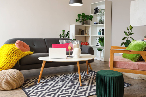 Interiér stylového obývacího pokoje s šedou pohovkou a moderním notebookem na konferenčním stolku - Fotografie, Obrázek