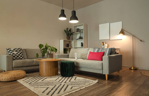 Interior de la elegante sala de estar con sofás grises y lámparas brillantes en la noche - Foto, imagen