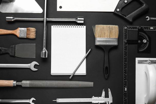 Набір будівельних інструментів, блокнот і ручка на чорному тлі - Фото, зображення