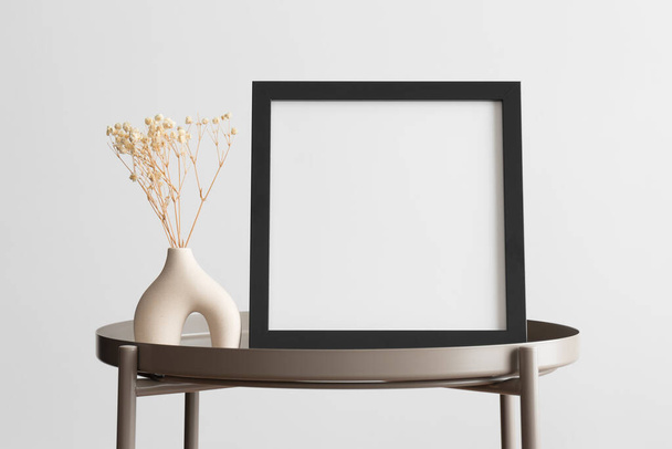 Black square frame mockup with a gypsophila decoration on the beige table. - Photo, Image