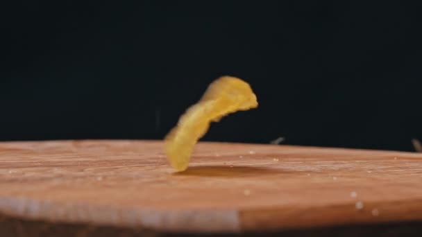 As batatas fritas de artesanato caem em câmera lenta em uma placa de madeira. Comida de plástico. Lanche de batata para fast food pouco saudável. Estilo de vida pouco saudável e carboidratos rápidos. - Filmagem, Vídeo