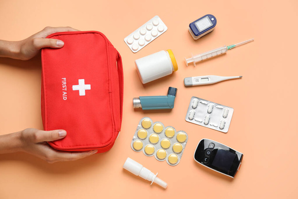 Mani femminili con kit di pronto soccorso e pillole su sfondo beige - Foto, immagini