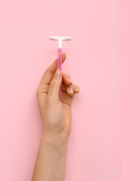 Mano femenina con afeitadora de seguridad sobre fondo rosa - Foto, Imagen