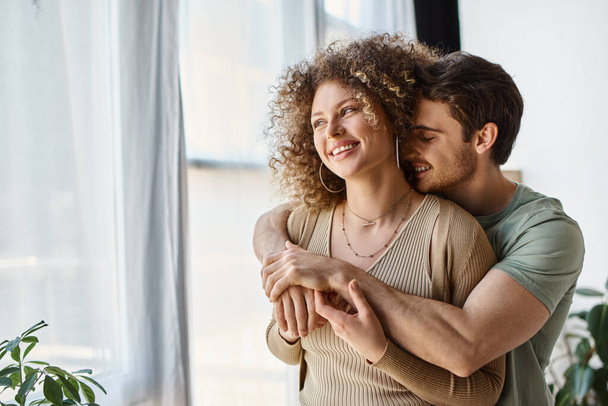 Couple in love of handsome man and curly woman at home in the morning, laughing and hugging - Photo, Image