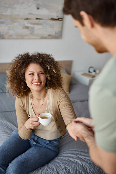 Ochtend koffie en heerlijke tijd met krullende jonge vrouw en brunette man, glimlachende gesprek - Foto, afbeelding