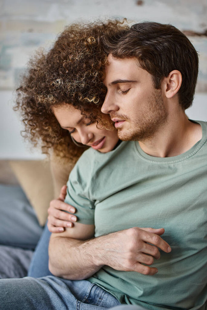 krullend jong vrouw en brunette man genieten van een warme knuffel, koesteren het rustige moment - Foto, afbeelding